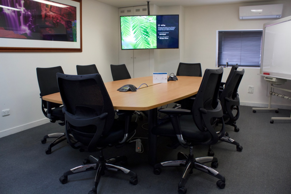 Private meeting room with large screen, whiteboard and boardroom table